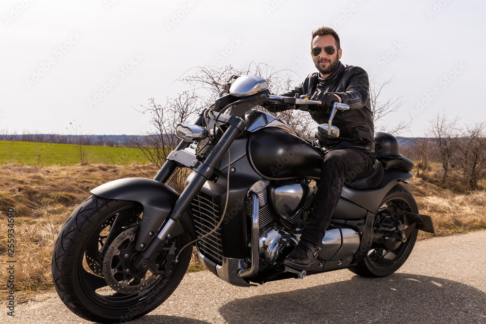  Handsome man on a black classic motorcycle