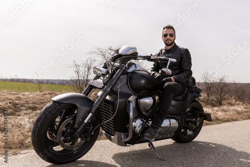  Handsome man on a black classic motorcycle
