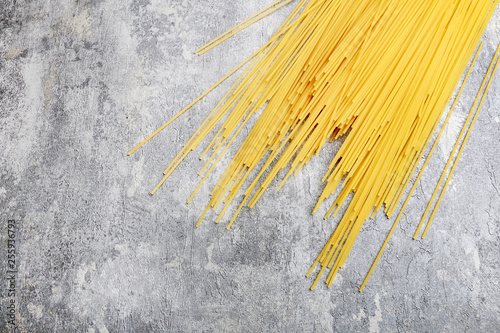 Mixed types and shapes of italian pasta on grey stone, background photo