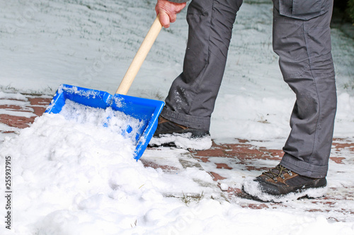 Man removing snow from the sidewalk after snowstorm.