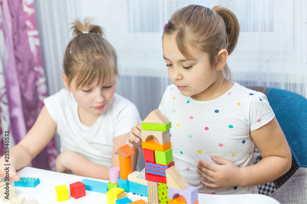 Children play with an educational toy on table in the children's room. Two kids playing with colorful blocks. Kindergarten educational games Children play with an educational toy on table in the children's room. Two kids playing with colorful blocks. Kindergarten educational games