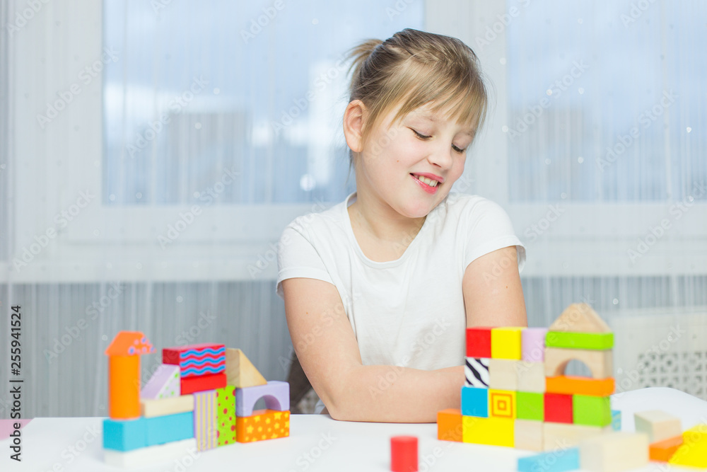 Schoolgirl girl play with educational toy on table in the children's room. Two kids playing with colorful blocks. Kindergarten educational games