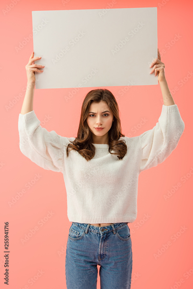 sad woman in white sweater holding empty board with copy space isolated on pink