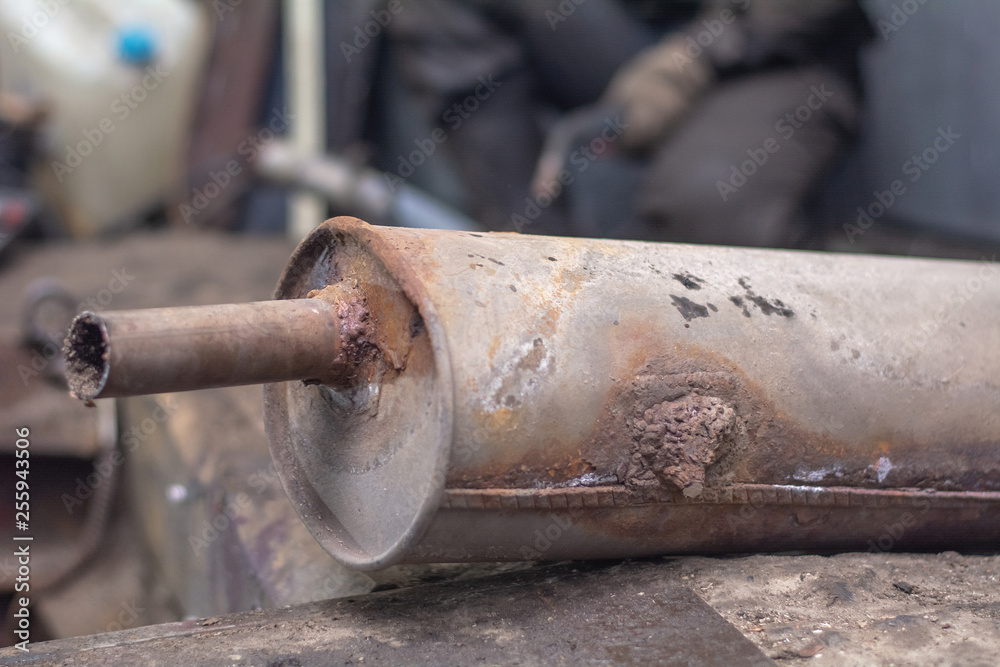 repairing of corrugation muffler of exhaust system in car workshop - serviceman welds the old silencer on car by argon welding repairing of corrugation muffler of exhaust system in car workshop - serviceman welds the old silencer on car by argon welding