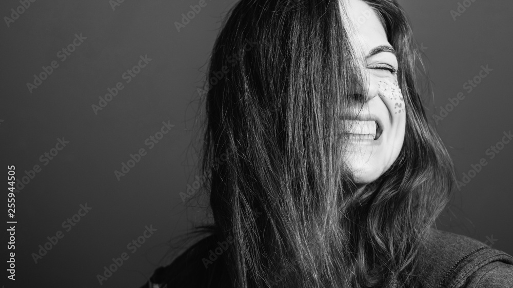 Woman grimacing. Rage facial expression. Bared teeth. Black and white portrait. Copy space.
