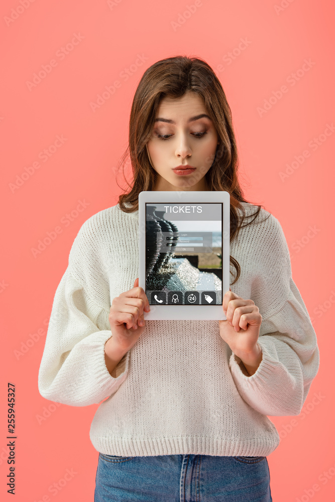 surprised young woman holding digital tablet with tickets app on screen isolated on pink surprised young woman holding digital tablet with tickets app on screen isolated on pink