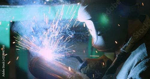 Welder. Industry. Work at the factory. Pipe welding. Electrode. Slow-motion. With people.Welder in welding mask photo