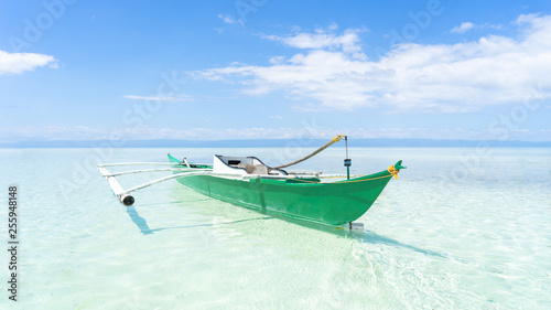 Side On Angle of A Traditional Filipino Fishing Boat Resting In Shallow Water On The Virgin Island of the Coast of Bohol, Philippines.