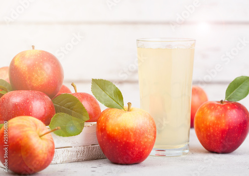 Glass of fresh organic apple juice with braeburn pink lady apples in box on wooden background with sun light