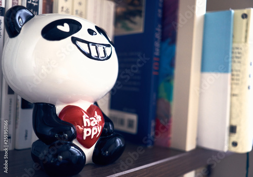 Close-up of panda shaped bank resting on a book shelf on a peaceful day.
