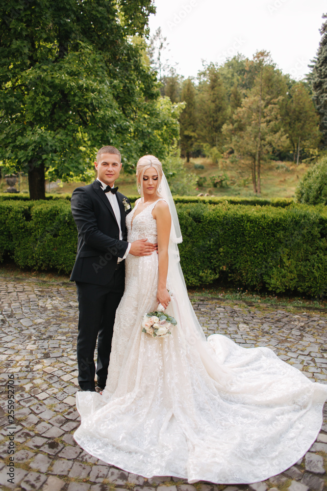 Beautiful wedding couple walking in the park. Bride with long white dress and stylish groom