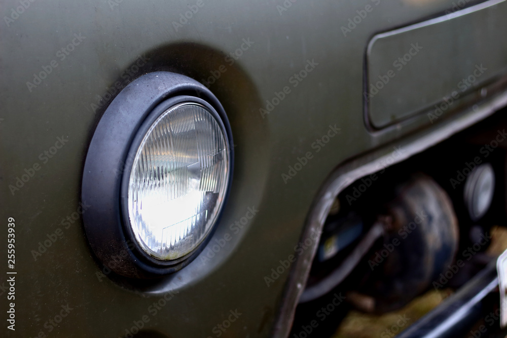 Glass headlight of an old retro russian truck SUV all-terrain khaki colour