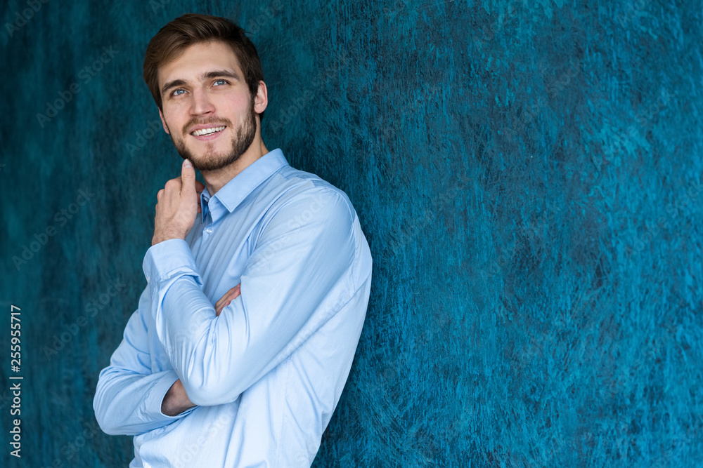 Portrait of handsome young man standing against blue wall with copy space. Portrait of handsome young man standing against blue wall with copy space.