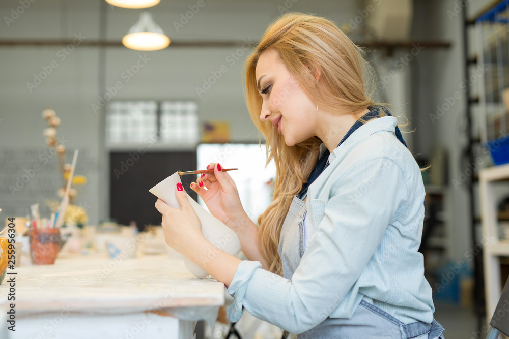 beautiful young girl paints a clay jug in a pottery workshop beautiful young girl paints a clay jug in a pottery workshop