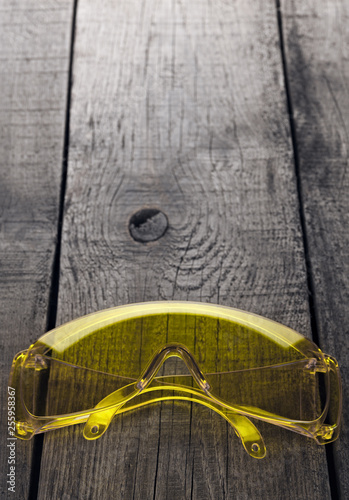 Eye protection glasses for repair and construction work, on a wooden background.
