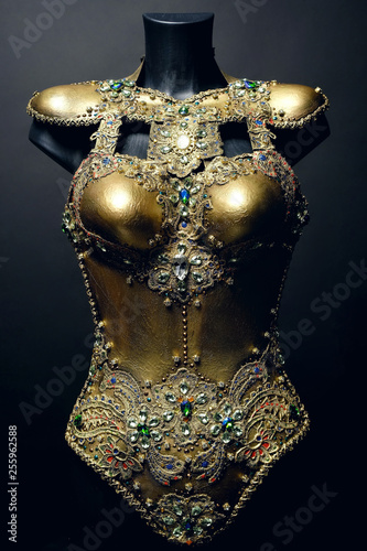 Gorgeous golden corset with precious stones, dark studio background