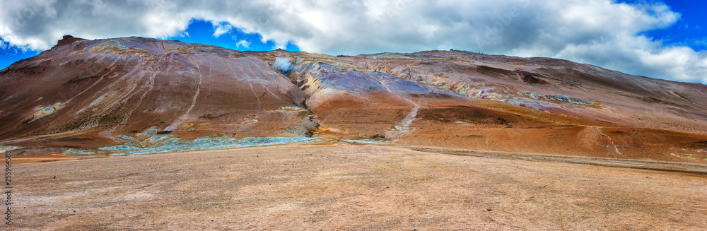 Namafjall Hverir geothermal area in Iceland. Stunning landscape of sulfur valley, panoramic view of Namafjall mountain and blue cloudy sky, travel background, tourist attraction