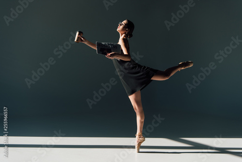 young ballerina in black dress dancing with newspaper and paper cup