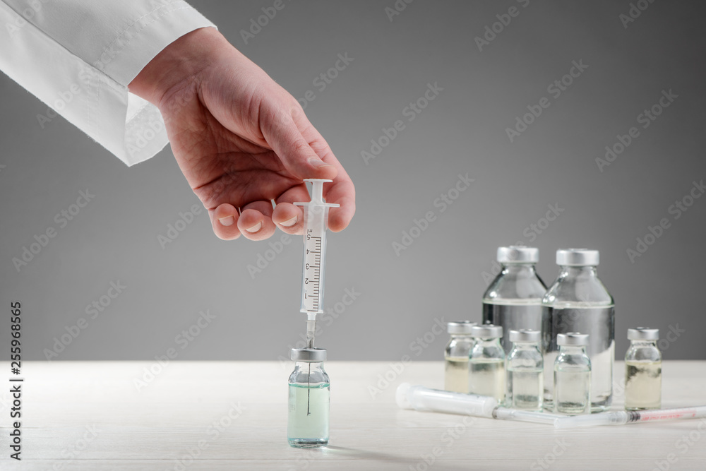 Doctor drawing vaccine into syringe Doctor drawing vaccine into syringe