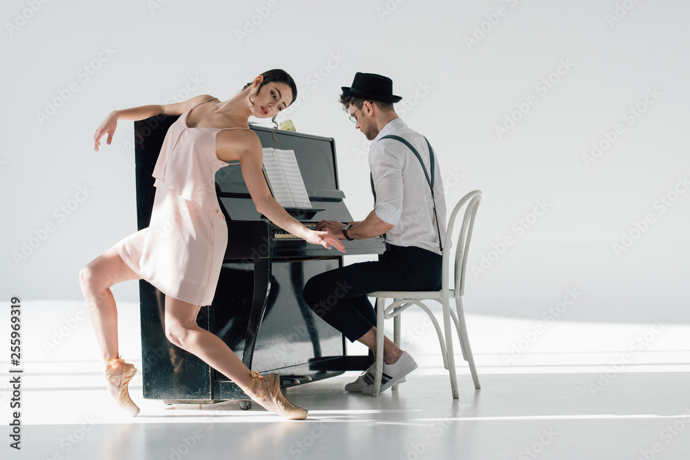 Fototapeta premium young musician playing piano while graceful ballerina dancing near him