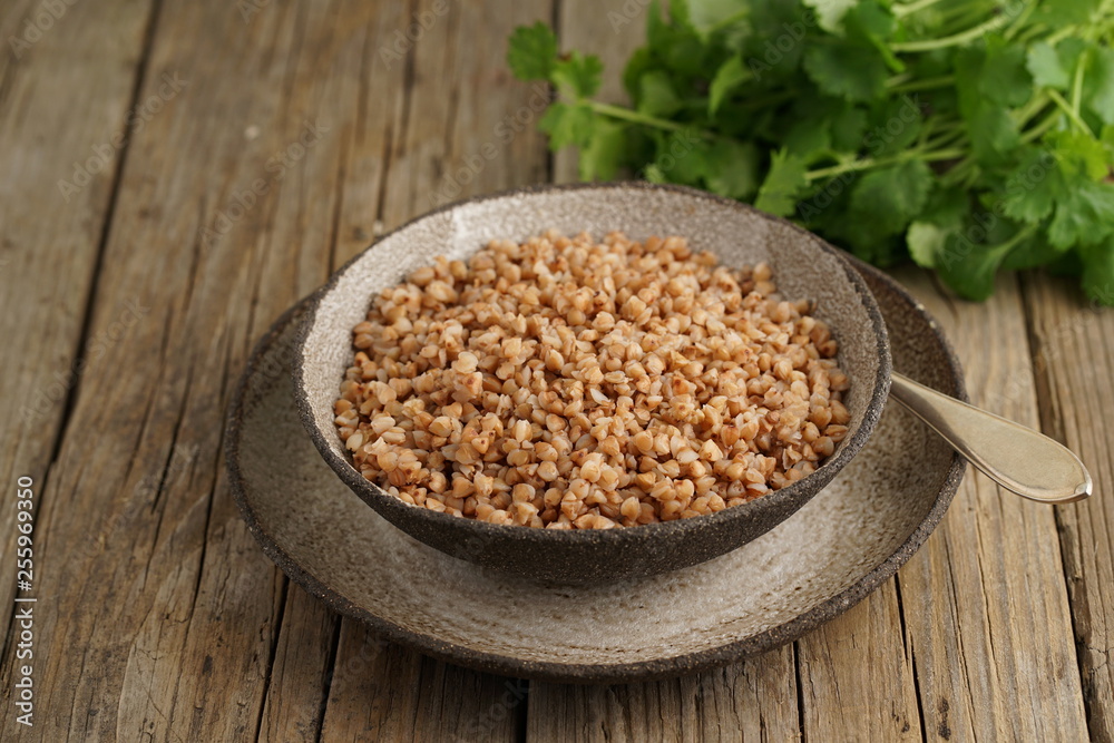 Boiled buckwheat porridge in black bowl and spoon on dark old wooden background, side view Boiled buckwheat porridge in black bowl and spoon on dark old wooden background, side view