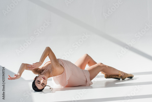 beautiful young ballerina lying on floor in sunlight