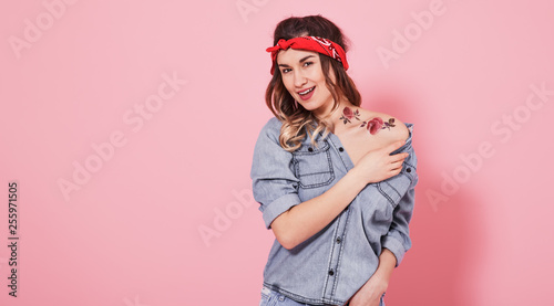 Portrait of a stylish girl in denim clothes on a pink background