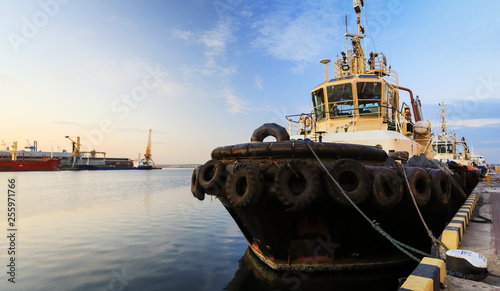 The tug is at the pier in the seaport.  Panoramic View of the evening port. Close-up. photo