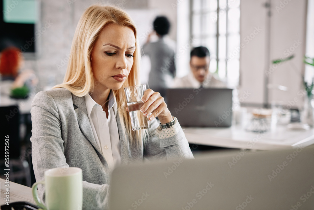Pensive businesswoman having a glass of water while working in the office. Pensive businesswoman having a glass of water while working in the office.