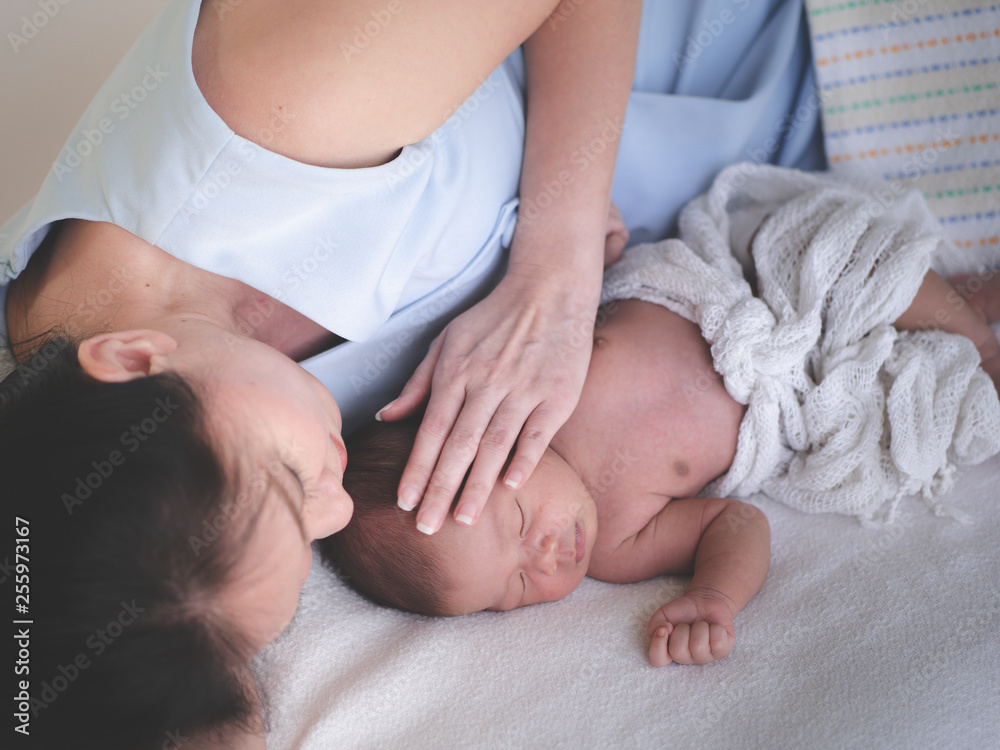Mother take care of Asian female newborn baby lying in bed and sunlight in the morning. Cute little girl three weeks old. Healthcare, love, relationship concept Mother take care of Asian female newborn baby lying in bed and sunlight in the morning. Cute little girl three weeks old. Healthcare, love, relationship concept
