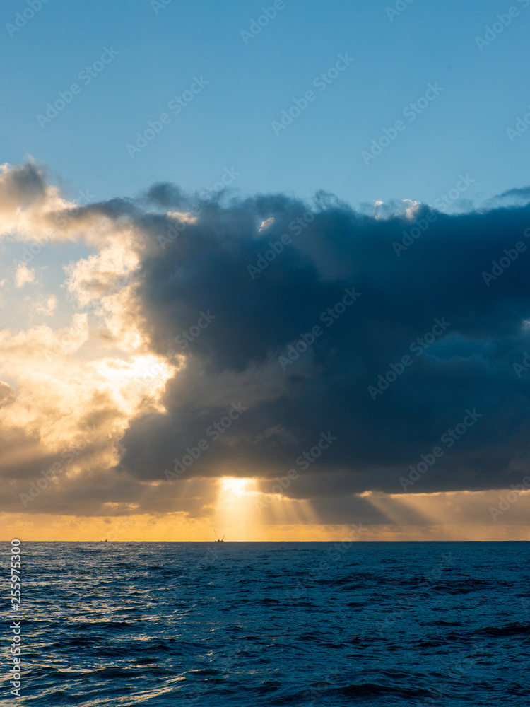 Ray of light through clouds above the ocean.