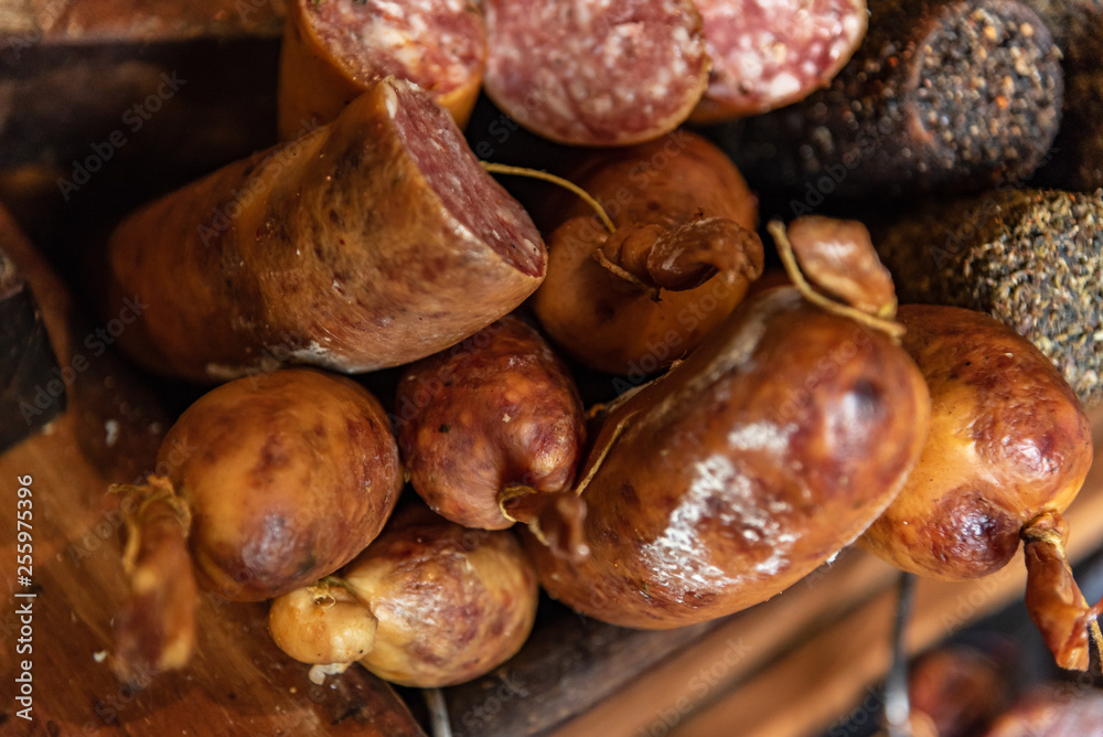 Variety of processed cold meat products with condiments. Assortment of different cold meats in a basket Variety of processed cold meat products with condiments. Assortment of different cold meats in a basket
