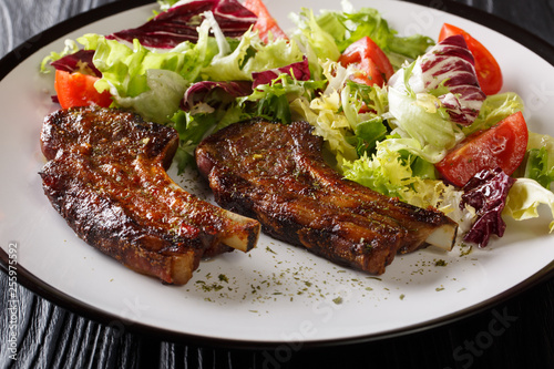 Delicious fried lamb chops served with fresh vegetable salad close-up on a plate. horizontal