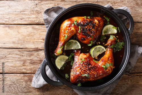 Tamarind chicken quarter leg with lime close-up in a frying pan. horizontal top view
