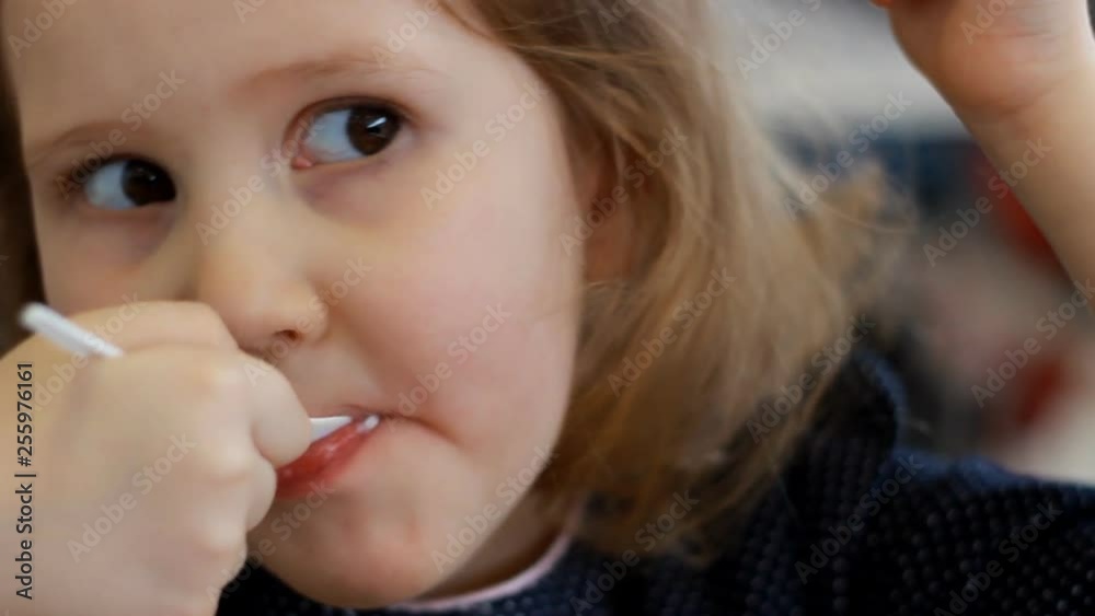 Baby girl eating dessert and drinking juice in the cafe. Portrait of a child who eats ice cream Baby girl eating dessert and drinking juice in the cafe. Portrait of a child who eats ice cream