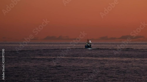 Fishing boat sailing into sunset.