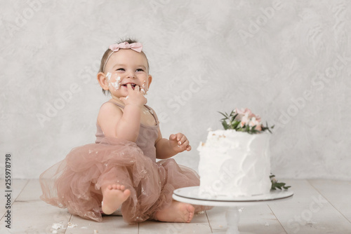 Obraz na plátne Portrait of a little cheerful birthday girl with the first cake