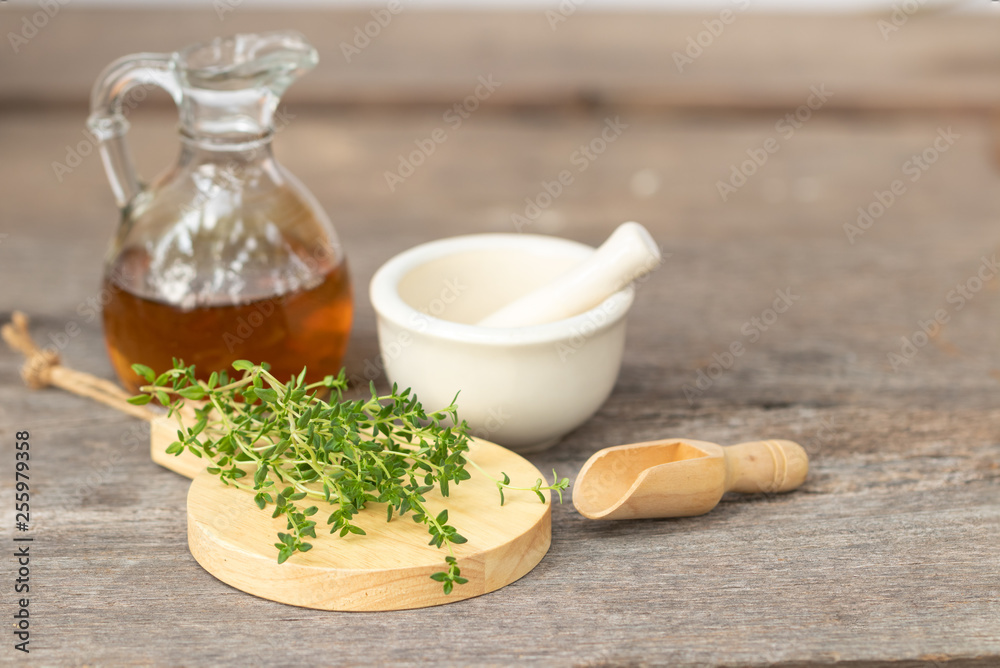 fresh thyme branch on wooden background over blur white mortar and oil in jar fresh thyme branch on wooden background over blur white mortar and oil in jar