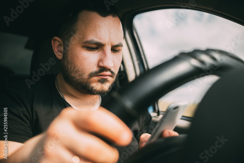 a man driving a car distracted by a smartphone