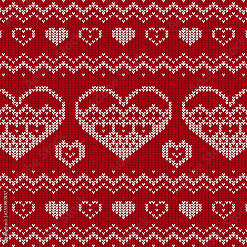 Red and white knitted background with hearts. Knitted pattern on a red background. Ornament. Valentine's Day background. Sweater texture hearts