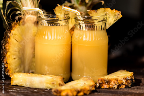 Pineapple juice and slice placed on a wooden table photo