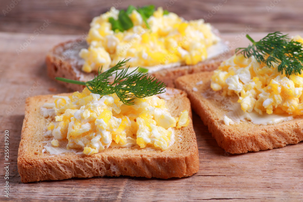 Crunchy toasted bread with scrambled eggs on rustic table Crunchy toasted bread with scrambled eggs on rustic table