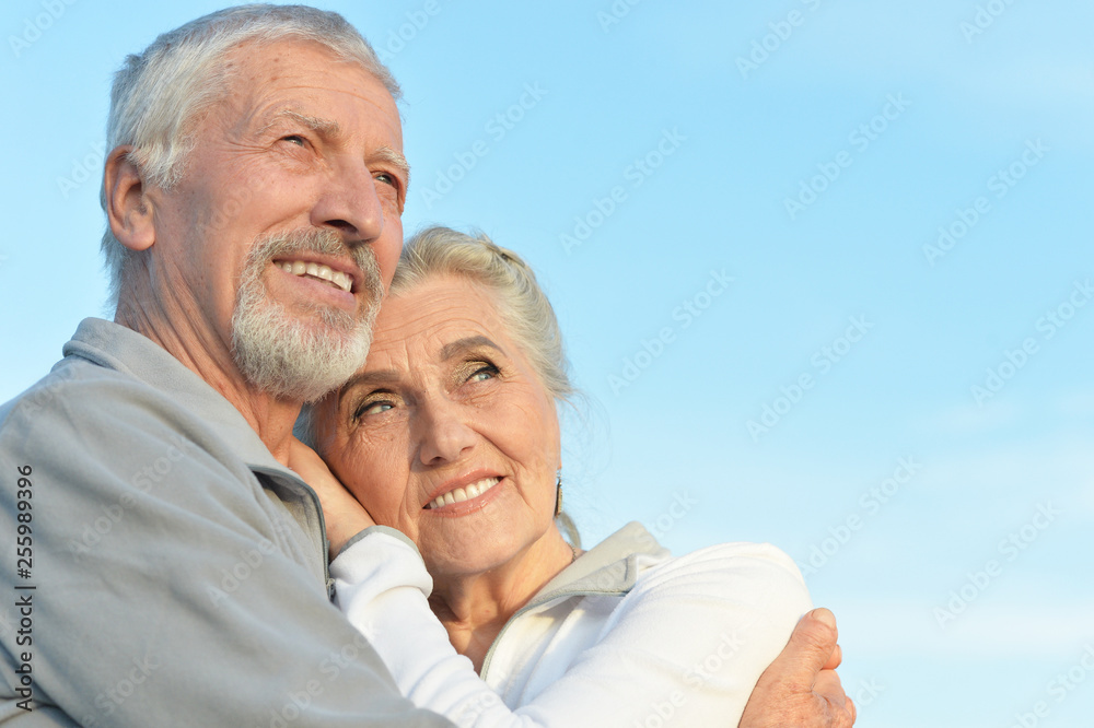 Portrait of happy senior couple hugging against blue sky Portrait of happy senior couple hugging against blue sky