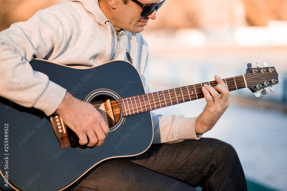 Young man sitting on steps playing guitar and singing, music concept