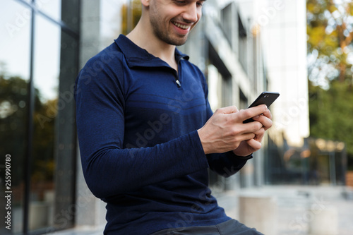 Croppped image of a sportsman using mobile phone