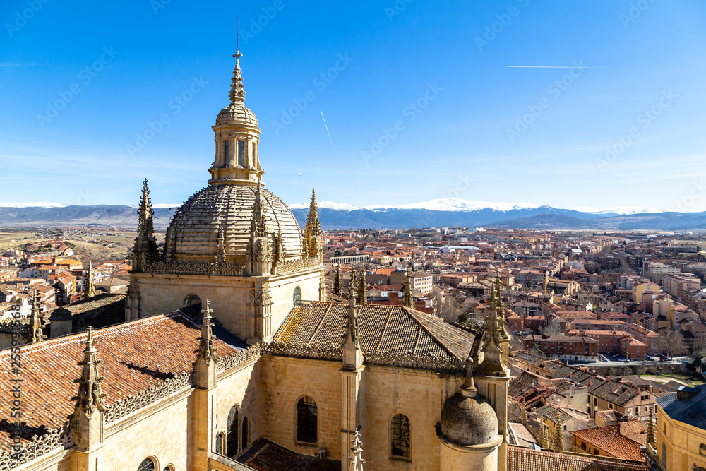 Obraz premium Segovia, Spain – View of the dome of the Cathedral and of Segovia old town from the top of the bell tower during Winter time. The snow capped peaks of Sierra de Guadarrama are visible behind