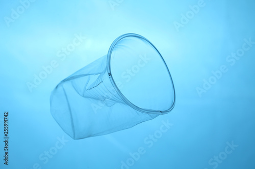 Canvas Print Plastic cup in blue water, plastic pollution of oceans.