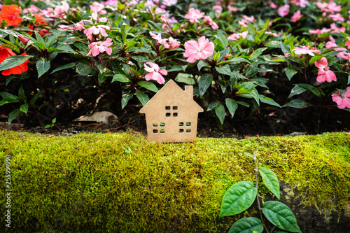 House model on green grass with colorful flower background , a symbol for construction , ecology, loan, mortgage, property or home. © sommart