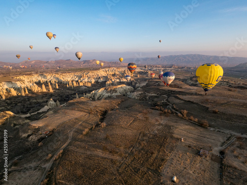 Hot air balloons flight - beautiful view of Goreme valley in Turkey. Panorama of Cappadocia - wide angel landscape with colorful hot balloons flying over mountain peaks. March, 2019
