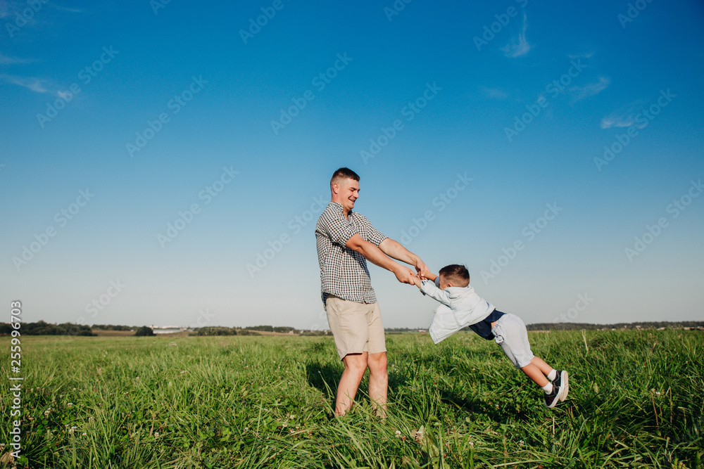 Cheerful dad playing with his child at the field Cheerful dad playing with his child at the field